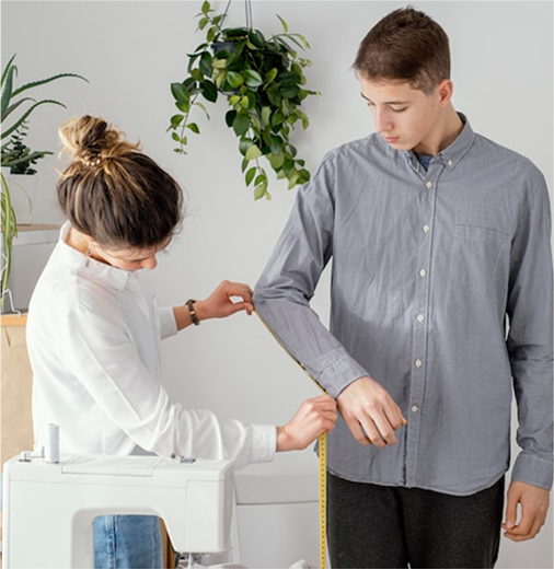 Seamstress measuring sleeve length on a man for custom shirt tailoring.