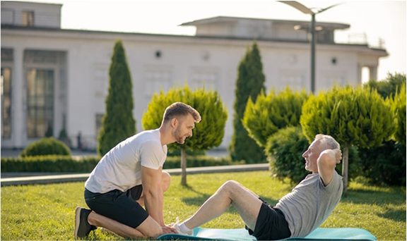 Senior man doing sit-ups with personal trainer outdoors